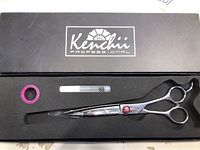 Hairdresser scissors in black box with foam lining, Kenchii logo on lid, included pink ring and clear tube.