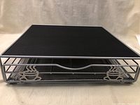 Front view of metal stand showing steaming coffee cup cutouts and drawer compartments for K-Cups.