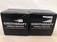 Two black packaging boxes of Idrotherapy Wrinkle Reducer anti-aging eye cream.