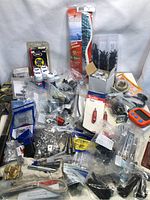 Wide view of lot displaying assorted industrial supplies, tools, spray cans, and small parts laid out on a grey backdrop.