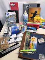 Photo of various brand new office supplies including notepads, rubber bands, Post-it notes, a stapler, and paper clips arranged on a flat surface