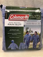 Packaged Coleman non-woven rain suit showing brand, size XL/2XL, features including waterproof breathable fabric, reflective tape front and back, two front pockets, and included clothing images.