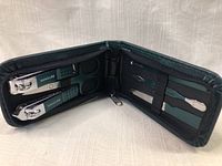 Open green zippered case displaying two metal nail clippers, scissors, cuticle pusher, and nail file with green grips.