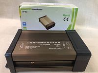 LED rainproof power supply laid flat in front of its original box with visible model and certification markings