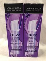 Front view of two boxed bottles of John Frieda Frizz Ease 4-in-1 Extra Strength Serum with pump dispensers visible through packaging.