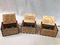 Photo of all three mini wooden music boxes side by side showing engraved lids and decorative wooden boxes