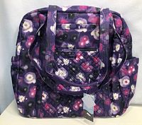 Photo of the front view of the Lug Sprinter tote bag featuring a purple floral pattern and front quilted pocket.
