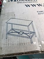 Box with line drawing of Monarch accent table showing rectangular top and geometric metal lower shelf.