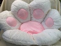 Photo of a new paw shaped cat bed with white plush toes and a pink center and toe pads.