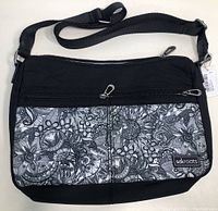 Front view of black Sakroots Willow Hobo purse showing floral black and white print, zippers and strap.