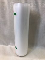 Roll of new vacuum sealer bags standing vertically, sealed with green adhesive strips, showing the smooth outer surface.