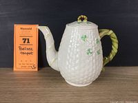 Front view of white Belleek basketweave teapot with shamrocks and vine-styled spout and handle