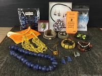 Full assortment of costume jewelry laid out on black surface showing necklaces, earrings, bracelets, a hair comb, and hair accessory pack.