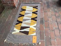 Full view of the rectangular wool wall hanging showing the fish design and attached wooden dowel.