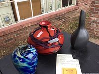 All three vases shown together on table outside brick wall and window background.
