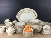 Full set of vintage Syracuse China Suzanne pattern including plates, cups, saucers, sugar bowl, creamer, and serving platters arranged on a table.