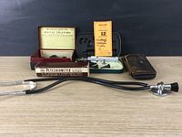 Collection showing Welch Allyn otoscope case, Petechiometer box and instructions, stethoscope, Dr. Young's rectal dilators box, and leather pouch likely for urology tools.