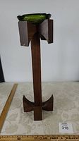 Front view of wood stand holding green glass ashtray, showing full height and base design.