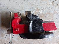 Side view of the strong red and black metal vise with a screw handle and 30 stamped on the side.