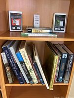 Wide view of assorted books on three shelves showing various titles on gardening, birds, and world heritage.