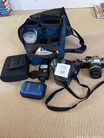 Overview of camera bag, cases, chargers, flash and camera with strap