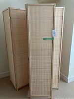 Front view of two folding screens, each with four panels connected with hinges. Light wood frames with woven panel inserts.