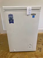 Front view of white Marathon chest freezer with warranty sticker and control dial.