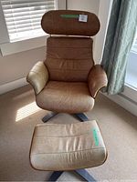 Front view of brown leather chair with matching ottoman on metal swivel bases