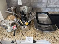 Overview of entire lot showing stainless steel pots, KitchenAid strainer, Klean Kanteen water bottle, and kitchen utensils on a granite countertop.