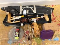 Full view of lot showing croquet bag with wooden mallets, goggles, two baseball gloves, frisbee, tennis balls, and foam roller with massager stick.