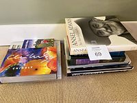 Two stacks of assorted coffee table books on carpeted floor