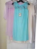 Lot of 6 vintage nightgowns hanging on hangers. Colors include pastel blue, light purple, cream, white, and others partially visible. Various lace and embroidered details visible.