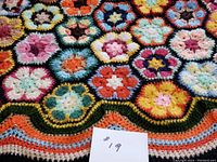 Close-up image showing colorful granny square crochet pattern and scalloped striped border with visible texture and color variation.