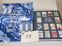 Photo showing folded Willow pattern tea towel in blue and white next to the hardcover book titled 'The Art of the Tea Towel'