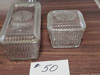 Photo showing both glass storage dishes with lids from the front, highlighting relative sizes and design.