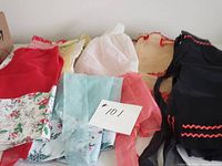 Seven vintage sheer half aprons of various colors and styles laid flat, highlighting mixed colors and floral patterns.