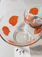Top-down angle showing the large glass bowl with orange leaf patterns and the small bowl secured in the metal holder hanging on the rim.