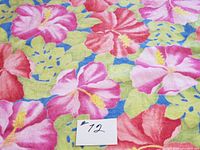 Close-up image showing the vibrant floral pattern of pink and red hibiscus flowers with green leaves on a blue background.