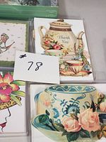 Photo showing vintage die cut note card with teapot and teacup illustration, a note card with pink and blue rose teacup, and partial views of other cards.