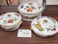 Photo of all three covered casseroles together showing the various fruit and vegetable designs with gold rims and handles