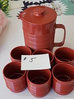 Photo showing the ribbed reddish-brown Rubbermaid pitcher with lid surrounded by six matching stackable mugs.