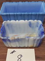 Two vintage slag glass rectangular decorative pieces on wooden surface, showing blue solid and marbled glass pieces with scalloped and ribbed edges.