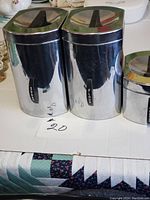 Photo showing vintage Kromex Sugar and Flour canisters with Bakelite lid handles and visible surface scratches