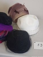 Group photo showing five vintage women's hats in assorted colors and styles on a flat surface.