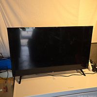 Front view of the 40 inch TCL TV on tabletop, showing black screen and stand legs.