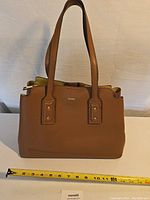 Front view of brown Aldo leather purse with double handles and a measuring tape showing size.