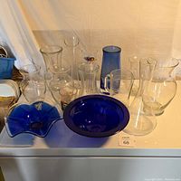 Wide angle photo showing all glassware items arranged on a flat surface under soft lighting.