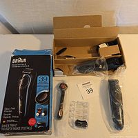 Left view showing beard trimmer, shaver attachment, combs, charging accessories in original box and sealed parts in plastic bags.