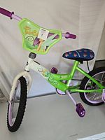 Front and side view of the children's bike showing green and white frame with Tinkerbell design and purple handlebars and pedals.