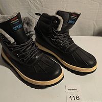 Side angle view of the pair of black boots with faux fur lining and rugged soles.